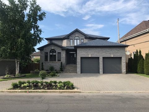 A large house with two garage doors is sitting on the side of the road.