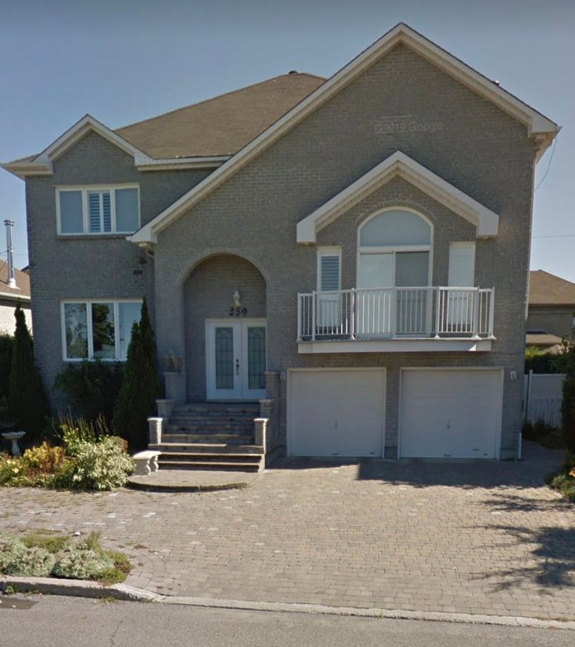 A large gray house with a balcony and stairs
