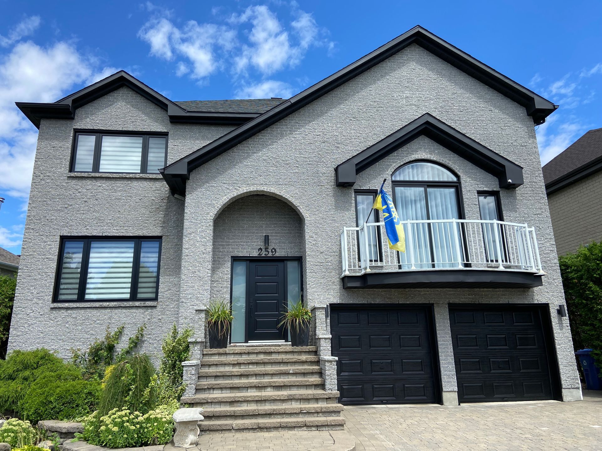 A large brick house with black garage doors and a balcony.