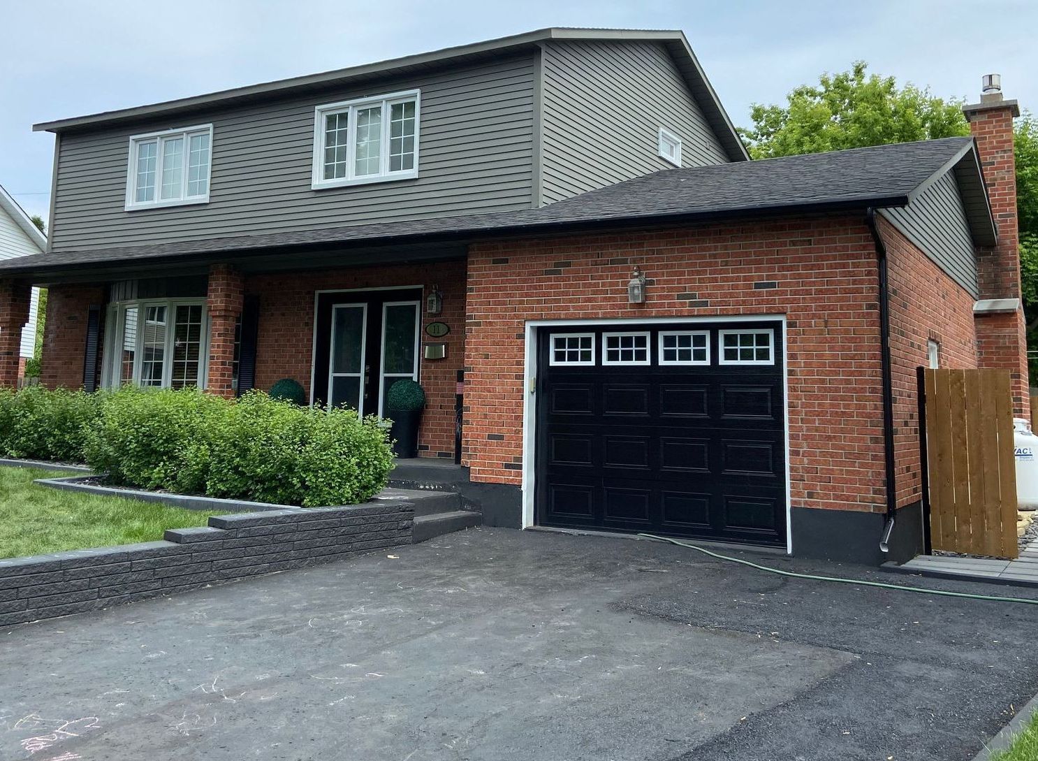 A brick house with a black garage door and a driveway.