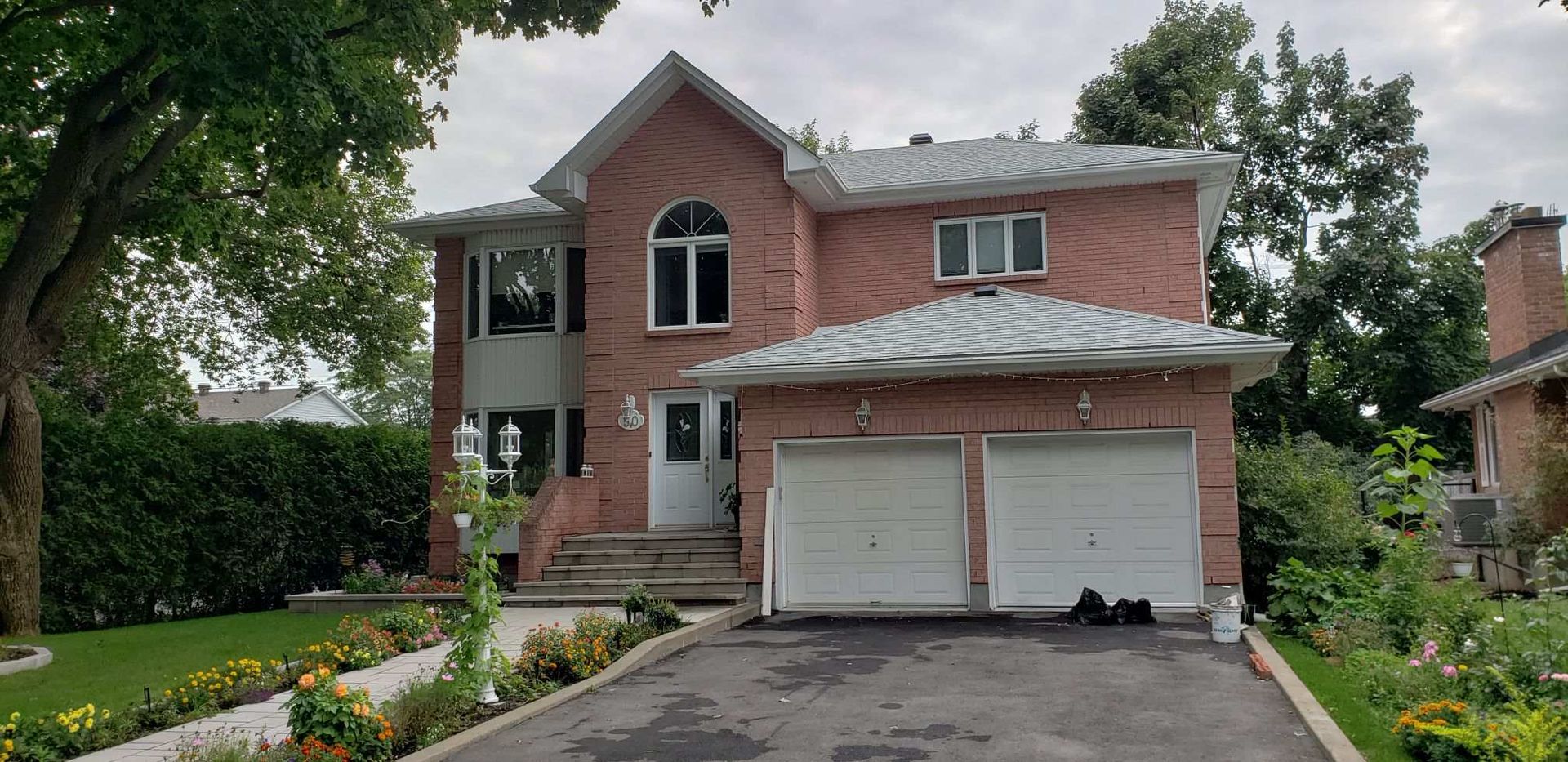 A large brick house with two garage doors and a driveway.