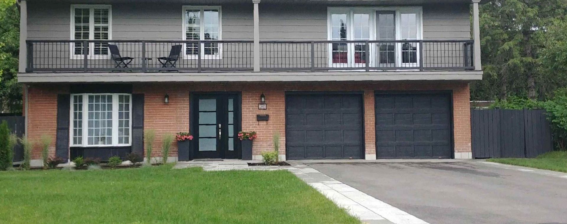 A large brick house with two garages and a balcony.