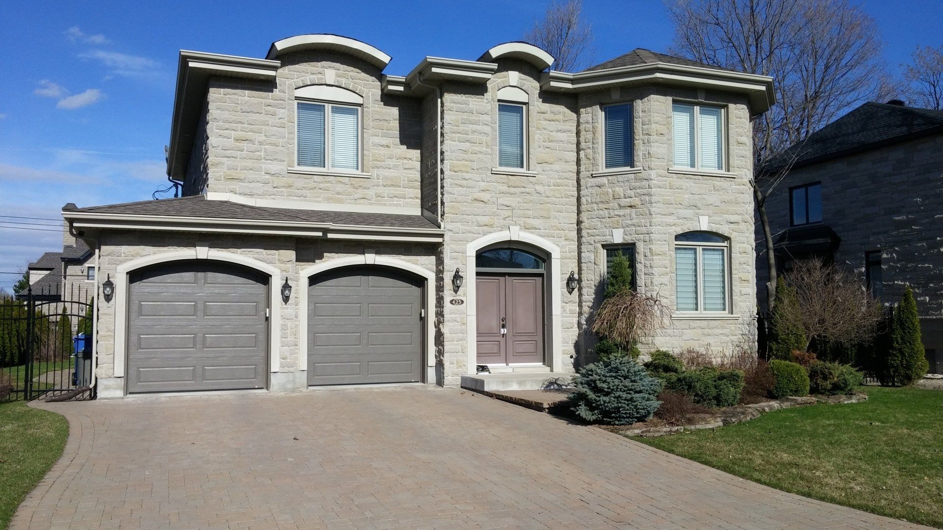 Une grande maison en brique avec deux portes de garage et une allée