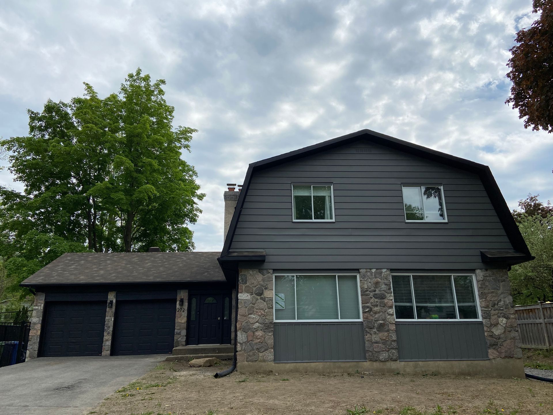 A large house with a gray siding and a black garage door