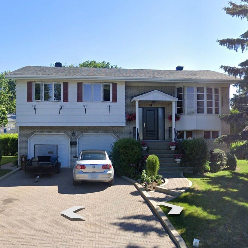 A white car is parked in front of a house