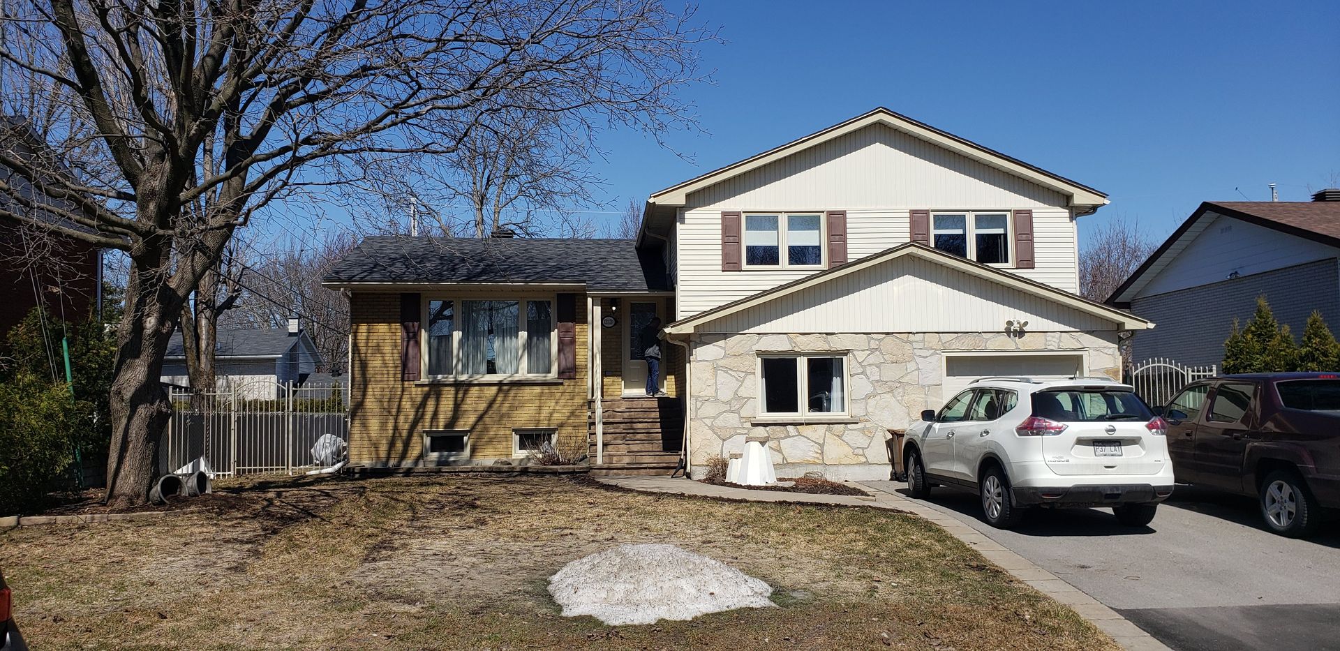 A white car is parked in front of a large house.