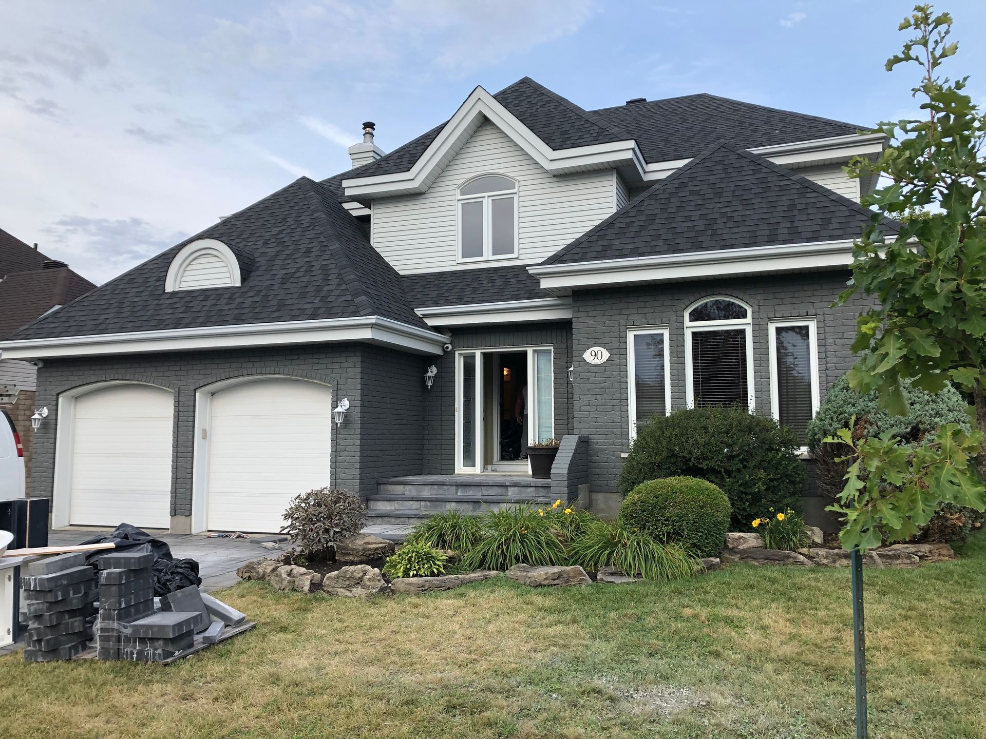 A large house with a black roof is sitting on top of a lush green lawn.