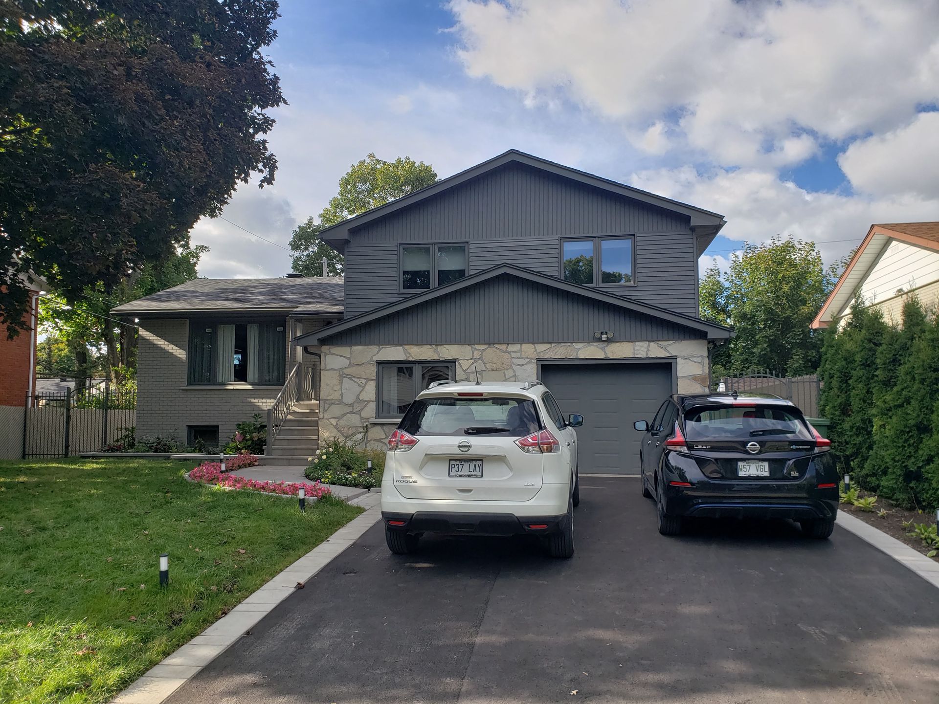 Two cars are parked in front of a large house.