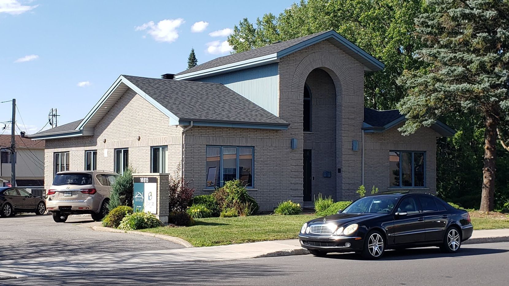 A black car is parked in front of a large house.