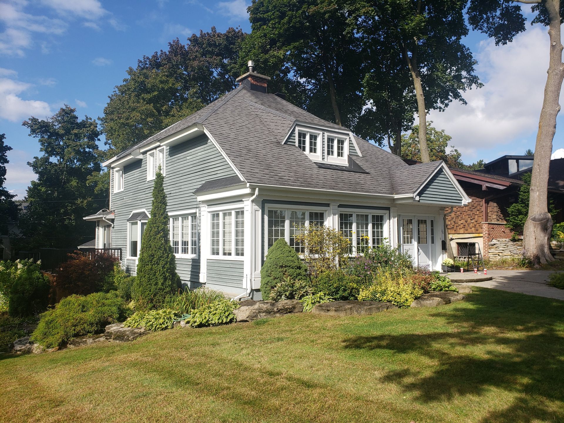 A house with a gray roof is surrounded by trees and grass