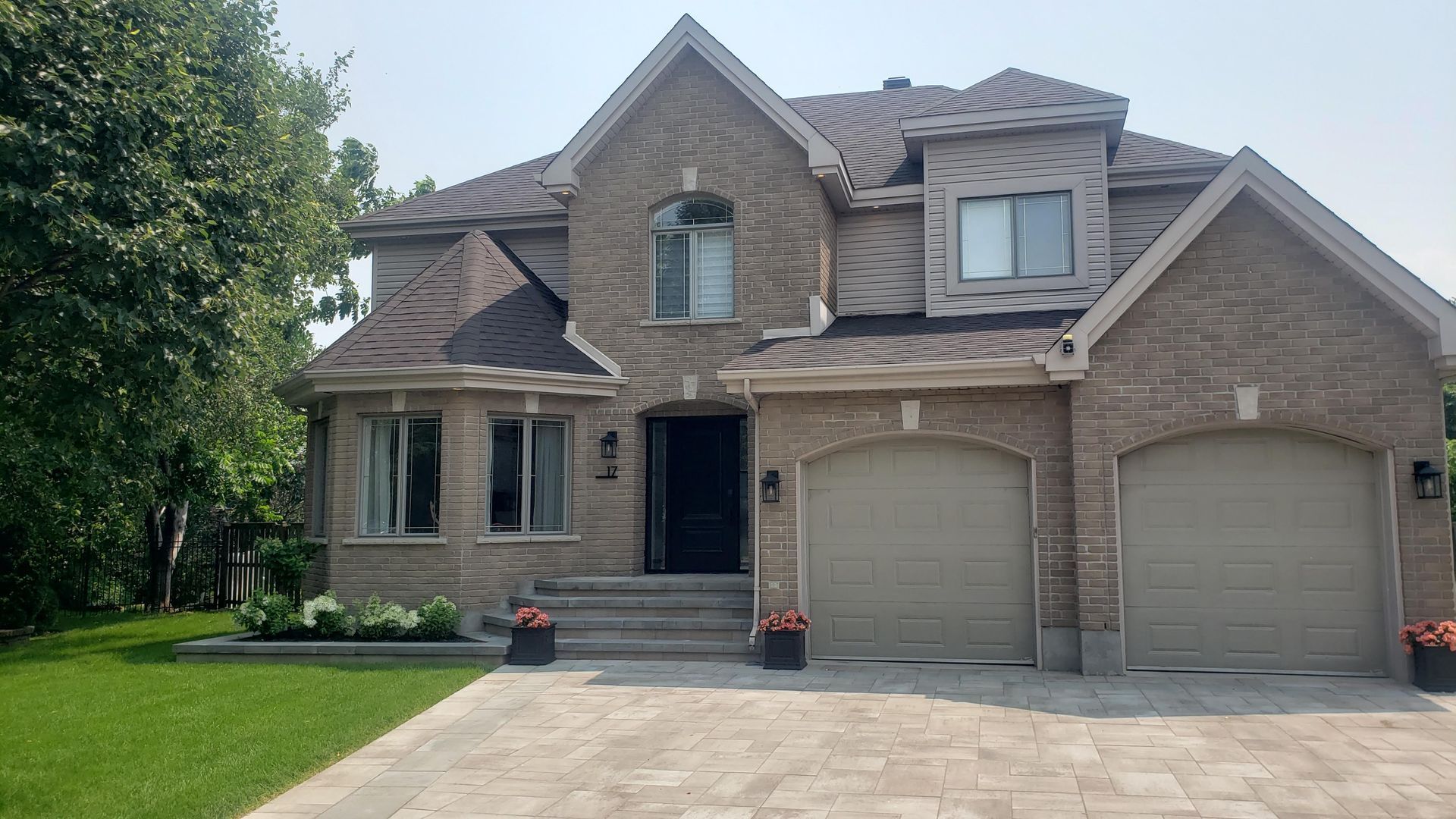 A large brick house with three garage doors and a driveway