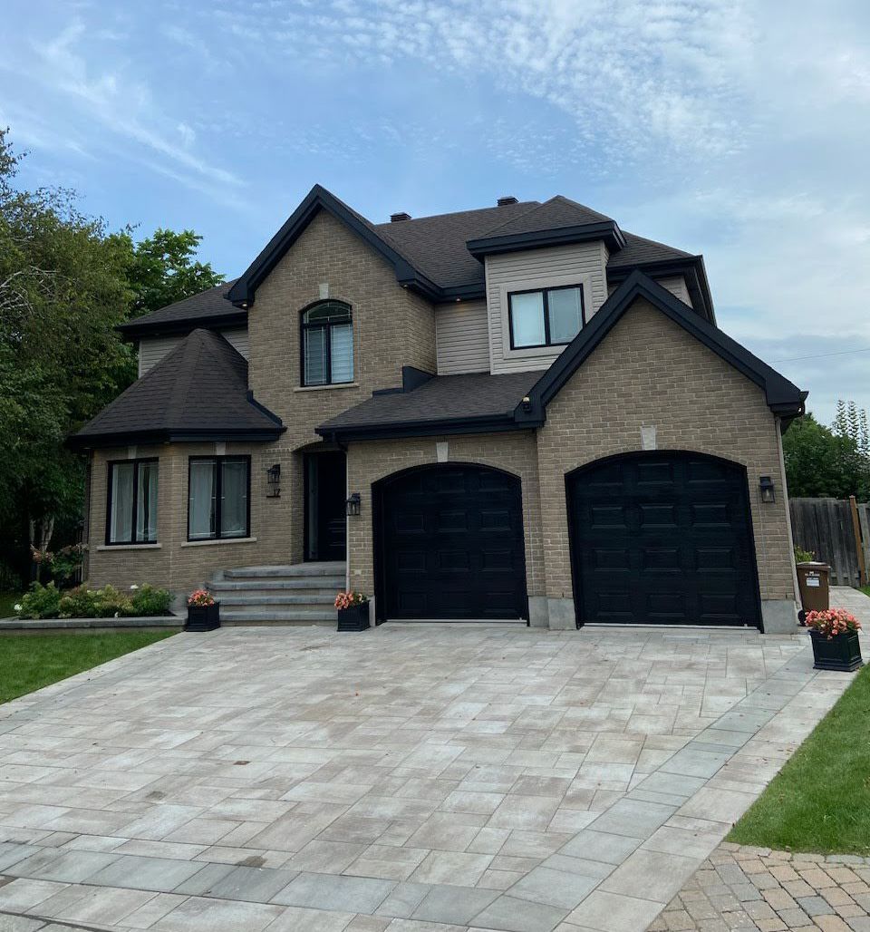 A large brick house with two black garage doors