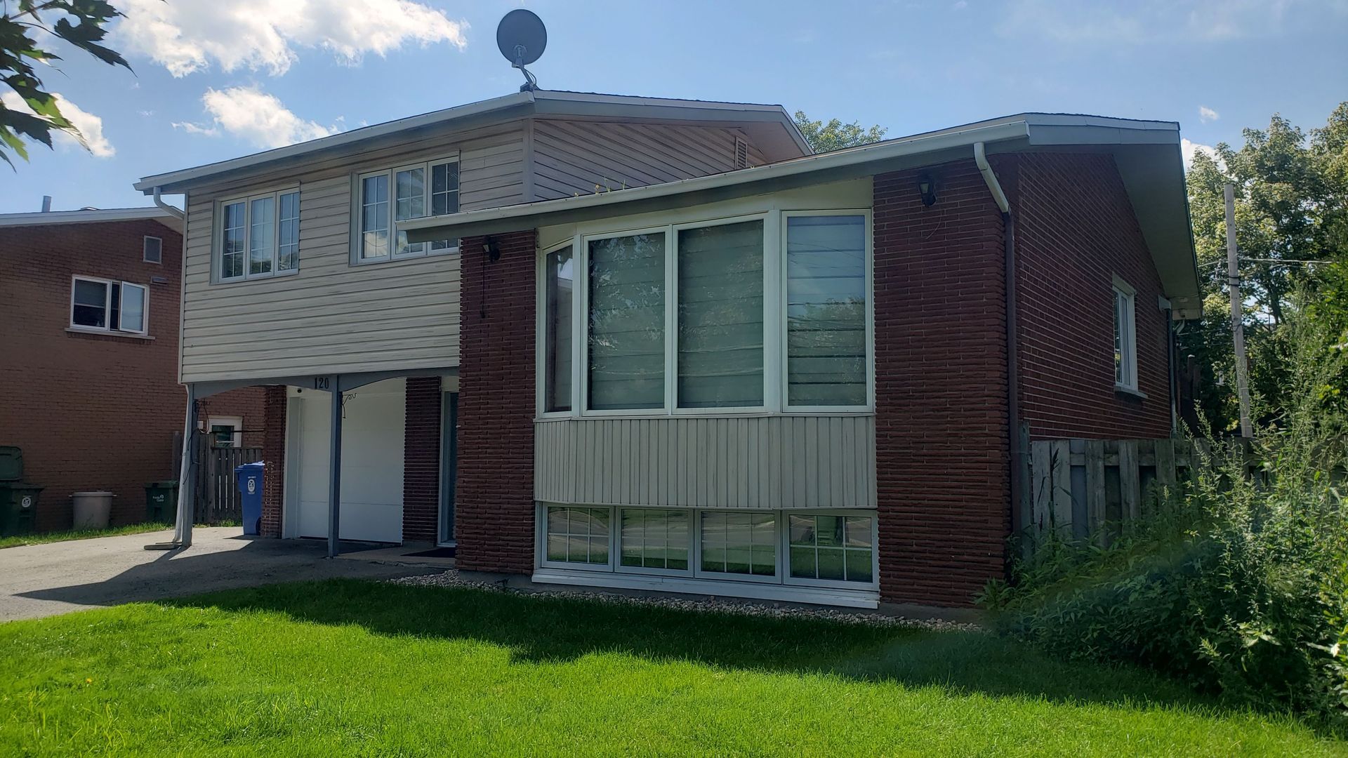 A large brick house with a lot of windows is sitting on top of a lush green lawn.