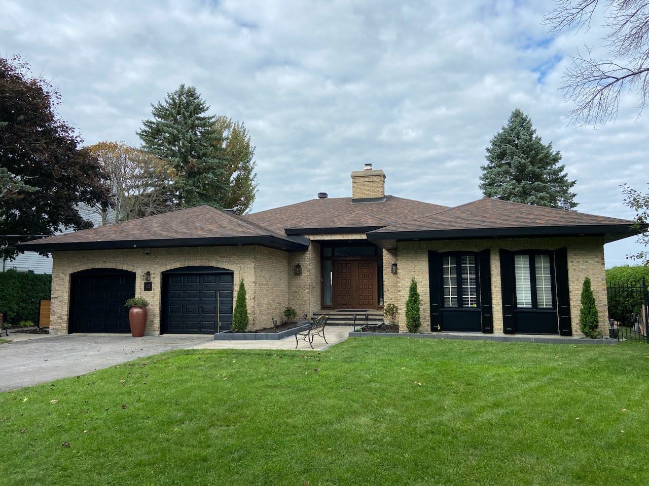 A large brick house with two garages and a large lawn in front of it.