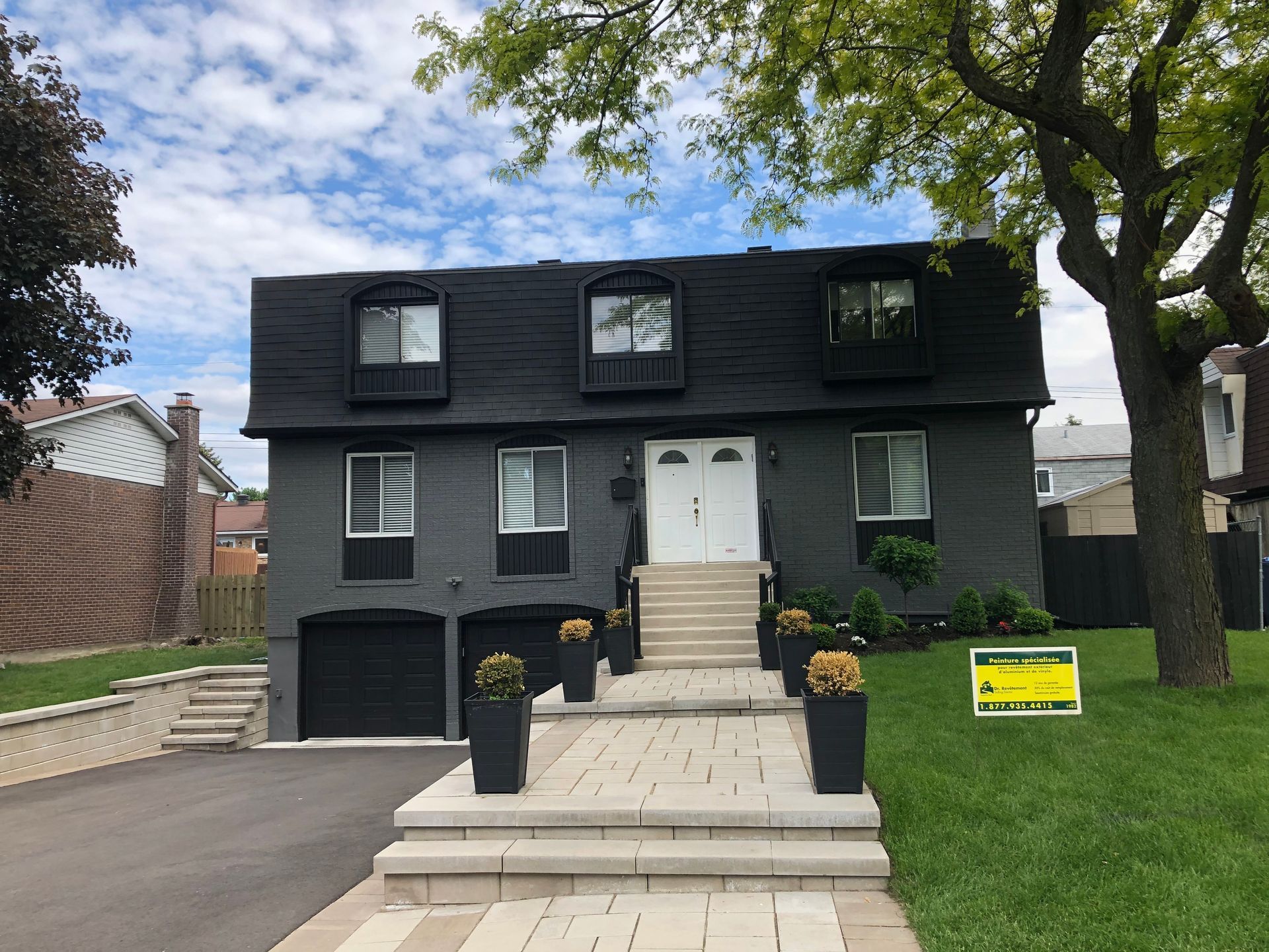 A black house with a yellow sign in front of it