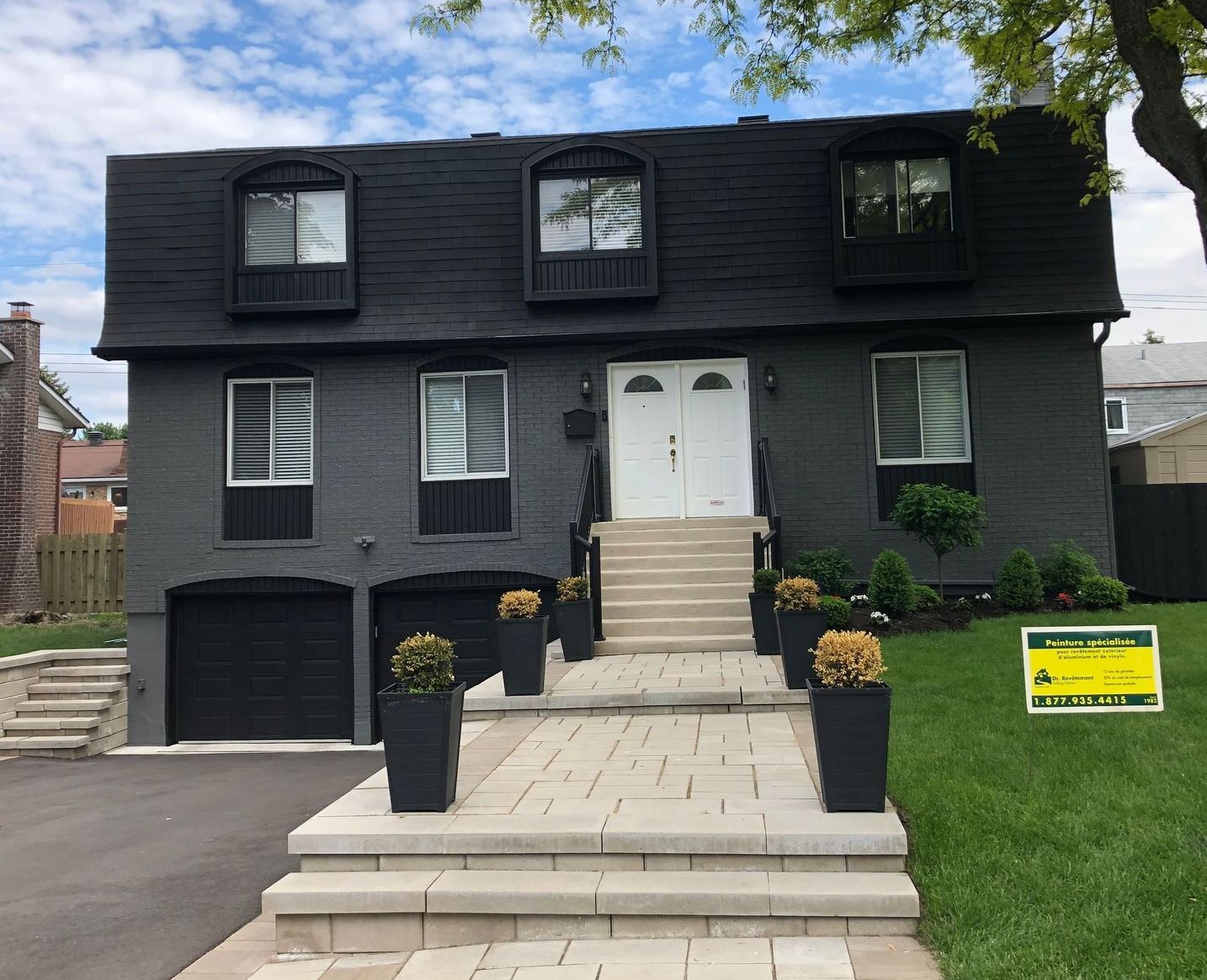 A black house with a yellow sign in front of it