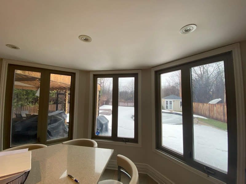 A room with a table and chairs and a lot of windows