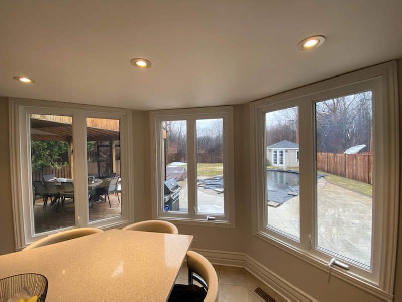 A kitchen with a table and chairs and a lot of windows.