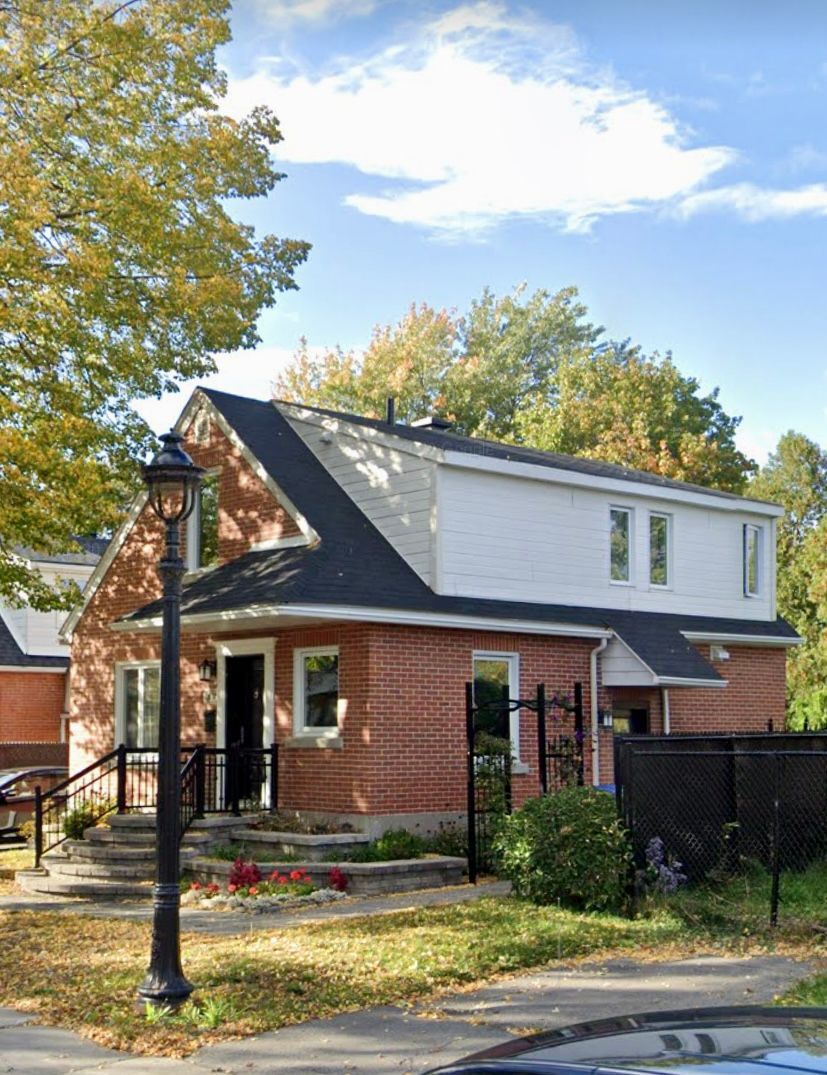 A brick house with a black roof and a car parked in front of it