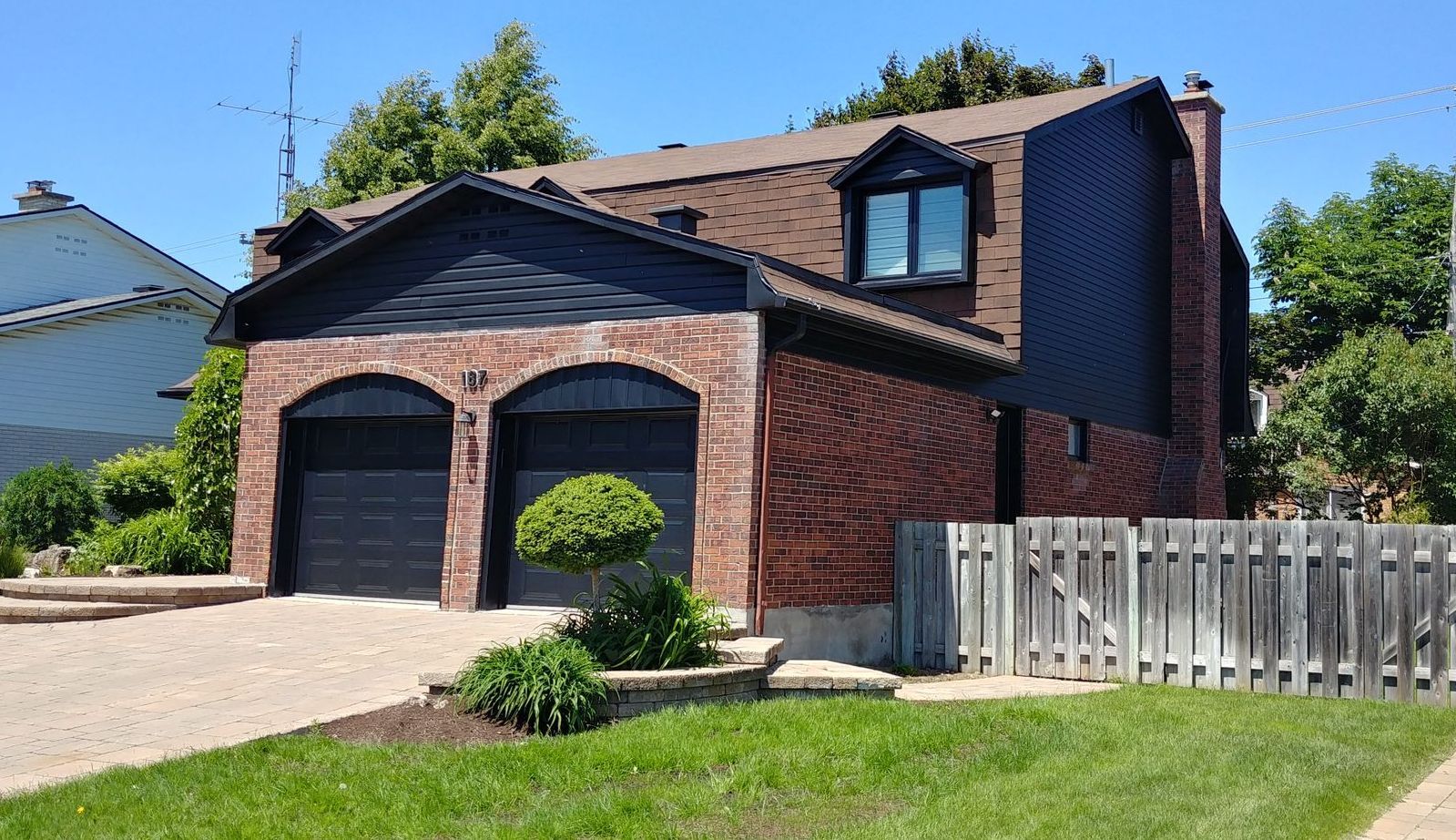 A brick house with black garage doors and a white picket fence