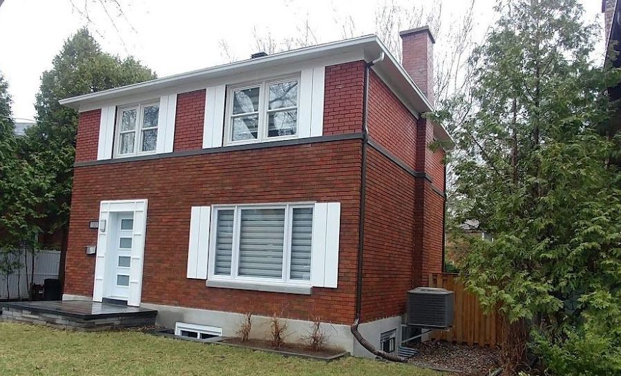 A red brick house with white shutters on the windows