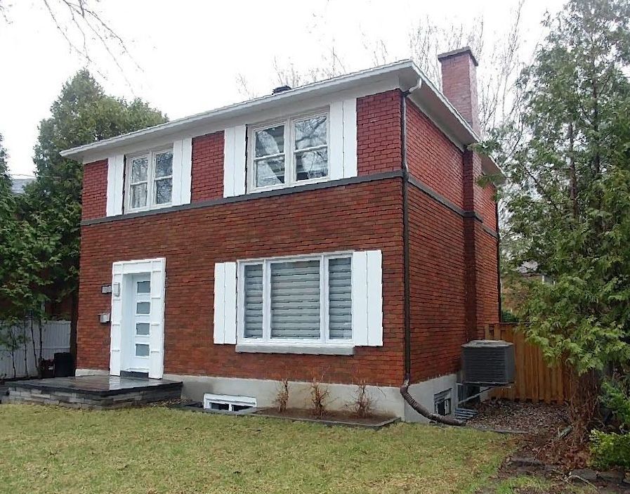 A red brick house with white shutters on the windows