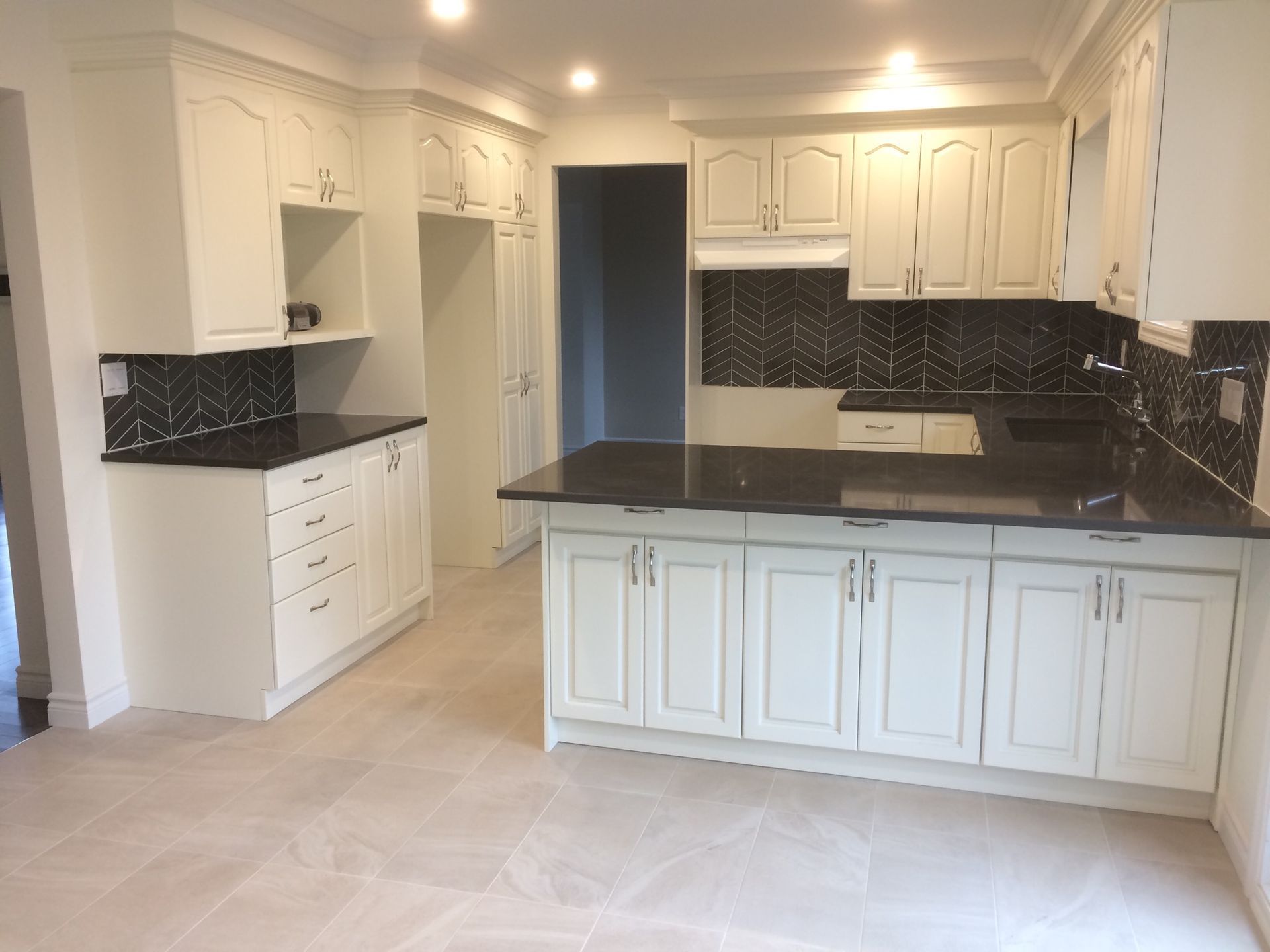 An empty kitchen with white cabinets and black counter tops