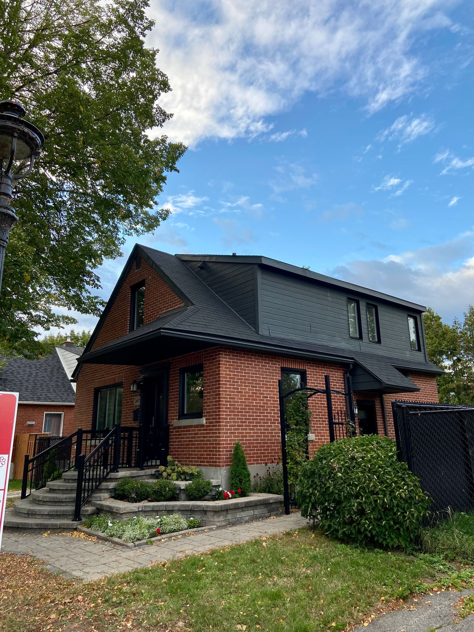 A brick house with a black roof is for sale.