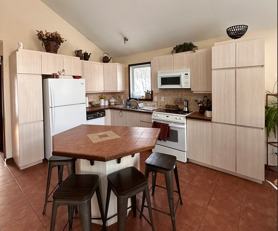 A kitchen with a table and stools and a refrigerator