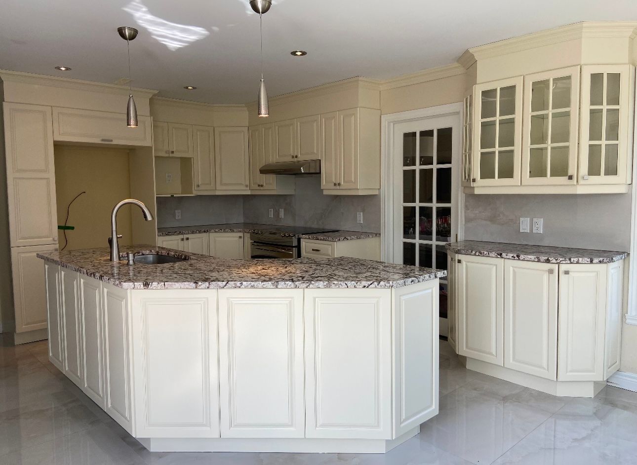 A kitchen with white cabinets and granite counter tops.