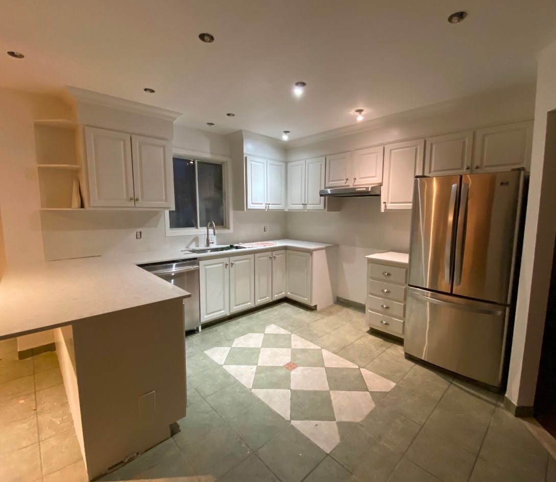 A kitchen with white cabinets and a stainless steel refrigerator.