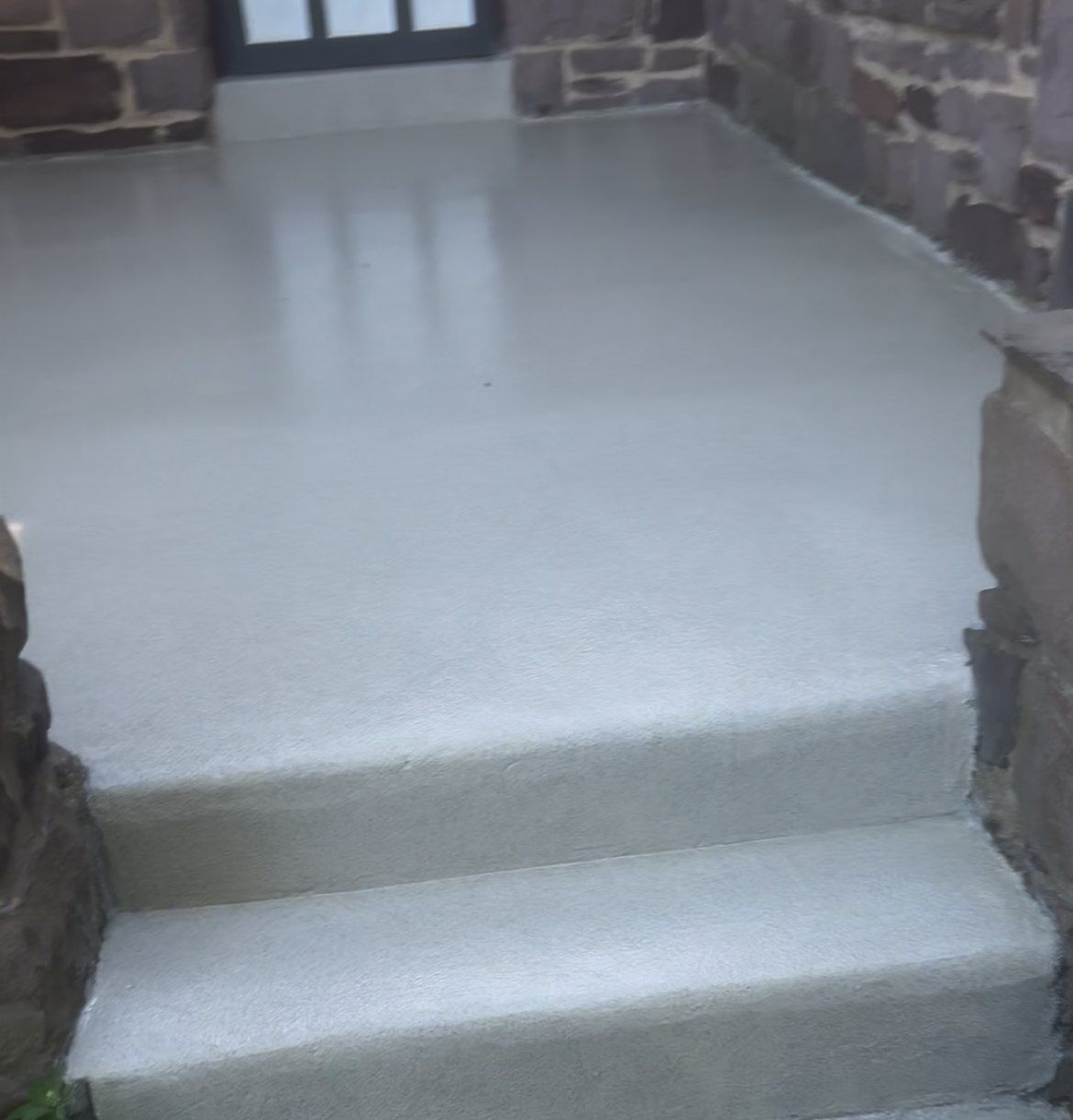 Coated concrete entry steps between stone walls