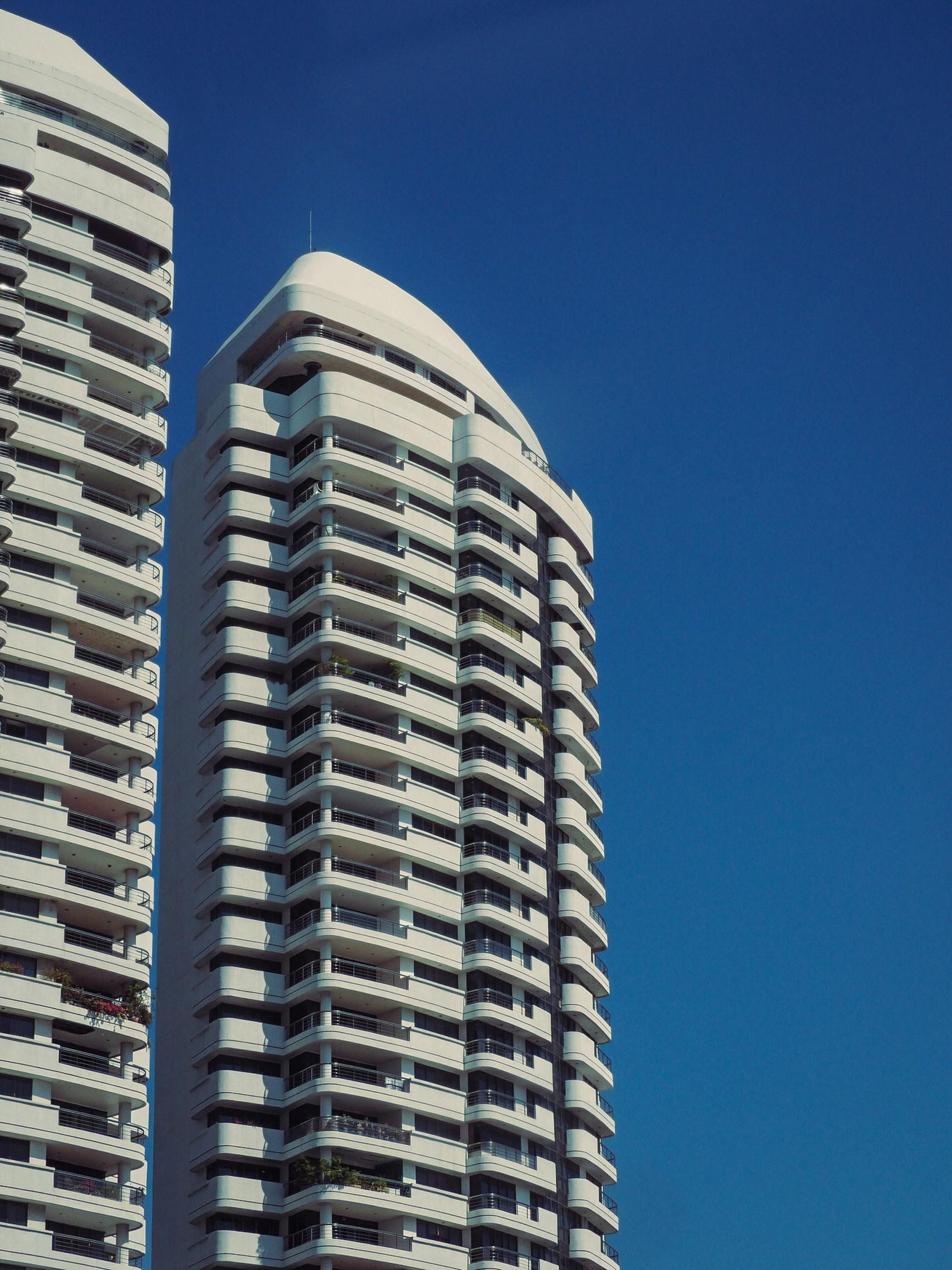 Tall white high-rise apartment towers against a clear blue sky.