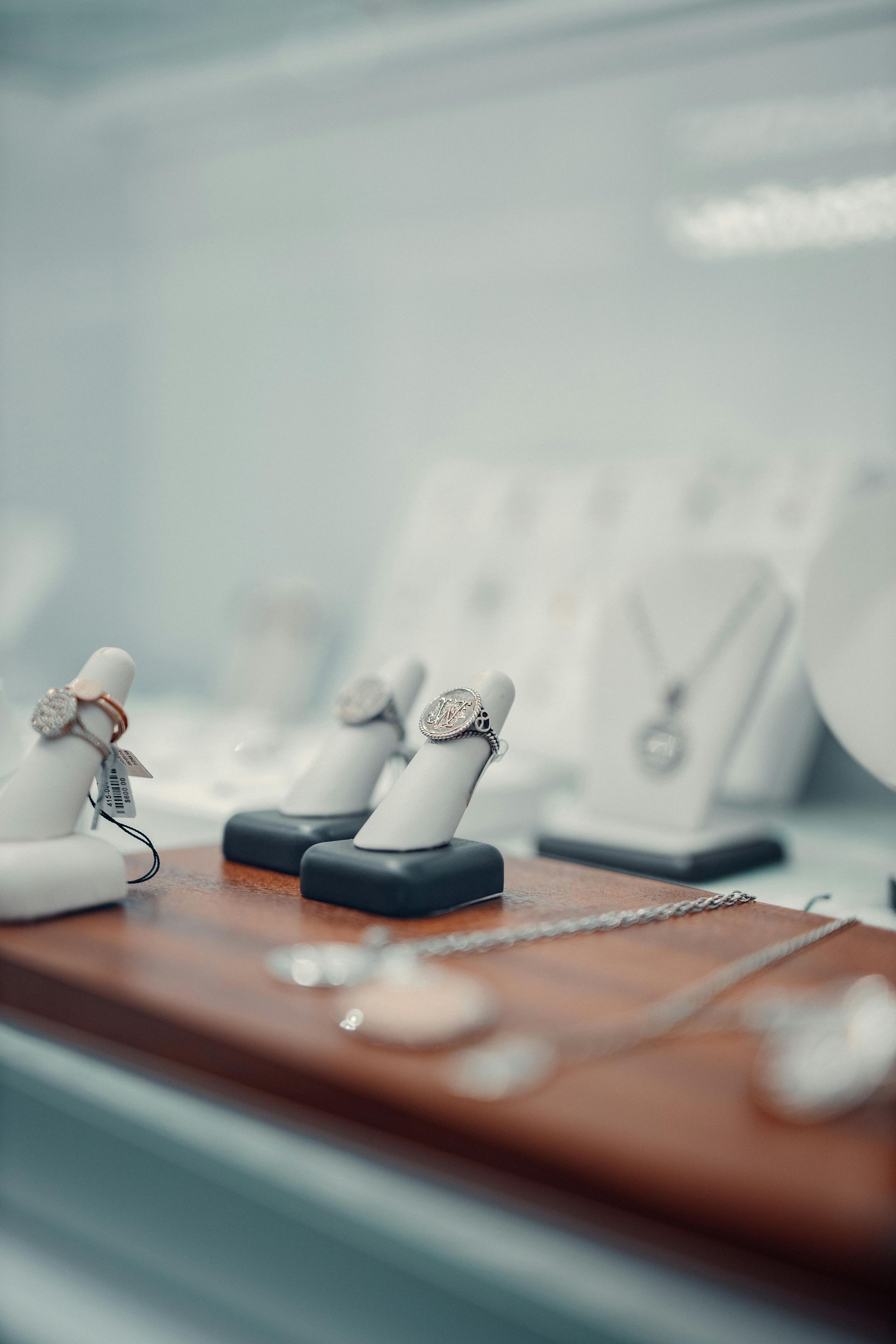 Small jewelry display with ring stands on a wooden counter, softly blurred in the background