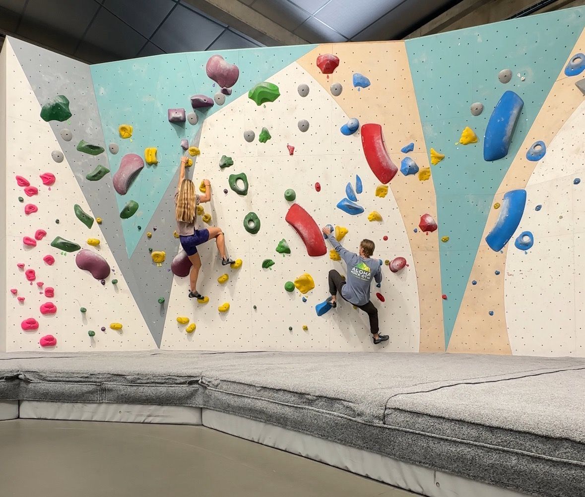 2 people bouldering on a climbing wall