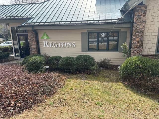 Regions bank building exterior with green logo, stone facade, and winter landscaping