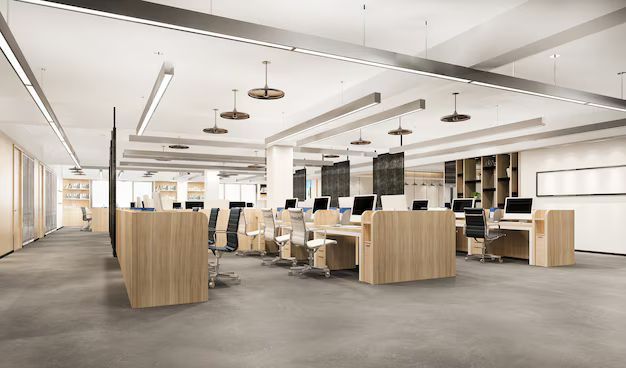 Modern office with light wood desks, computers, and overhead lighting.