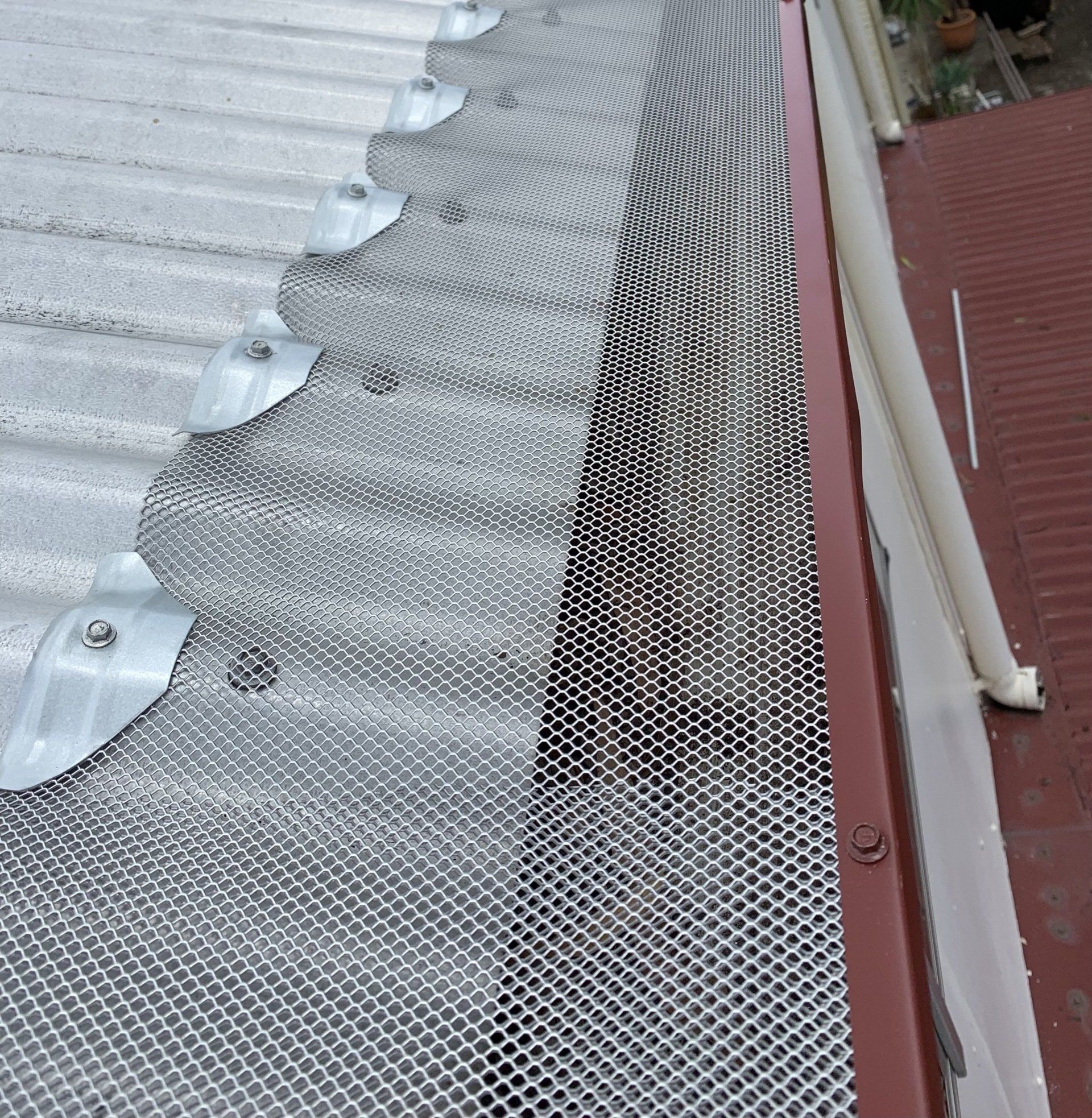 Metal mesh gutter guard installed on a corrugated metal roof.