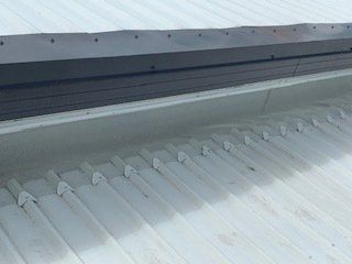 White corrugated metal roof with black trim and white metal clips along the edge.