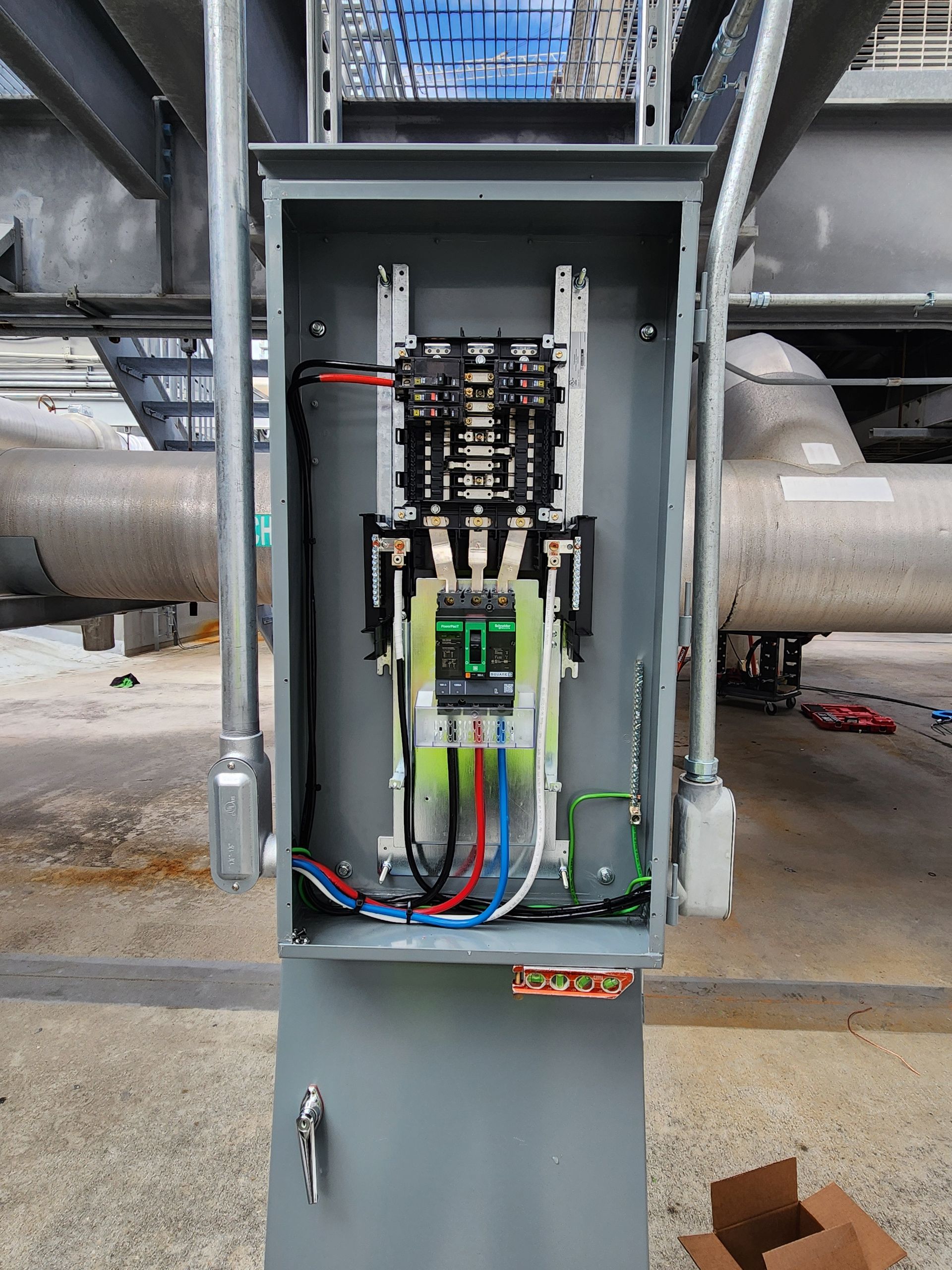 Open electrical control cabinet with wiring and relays in an industrial setting