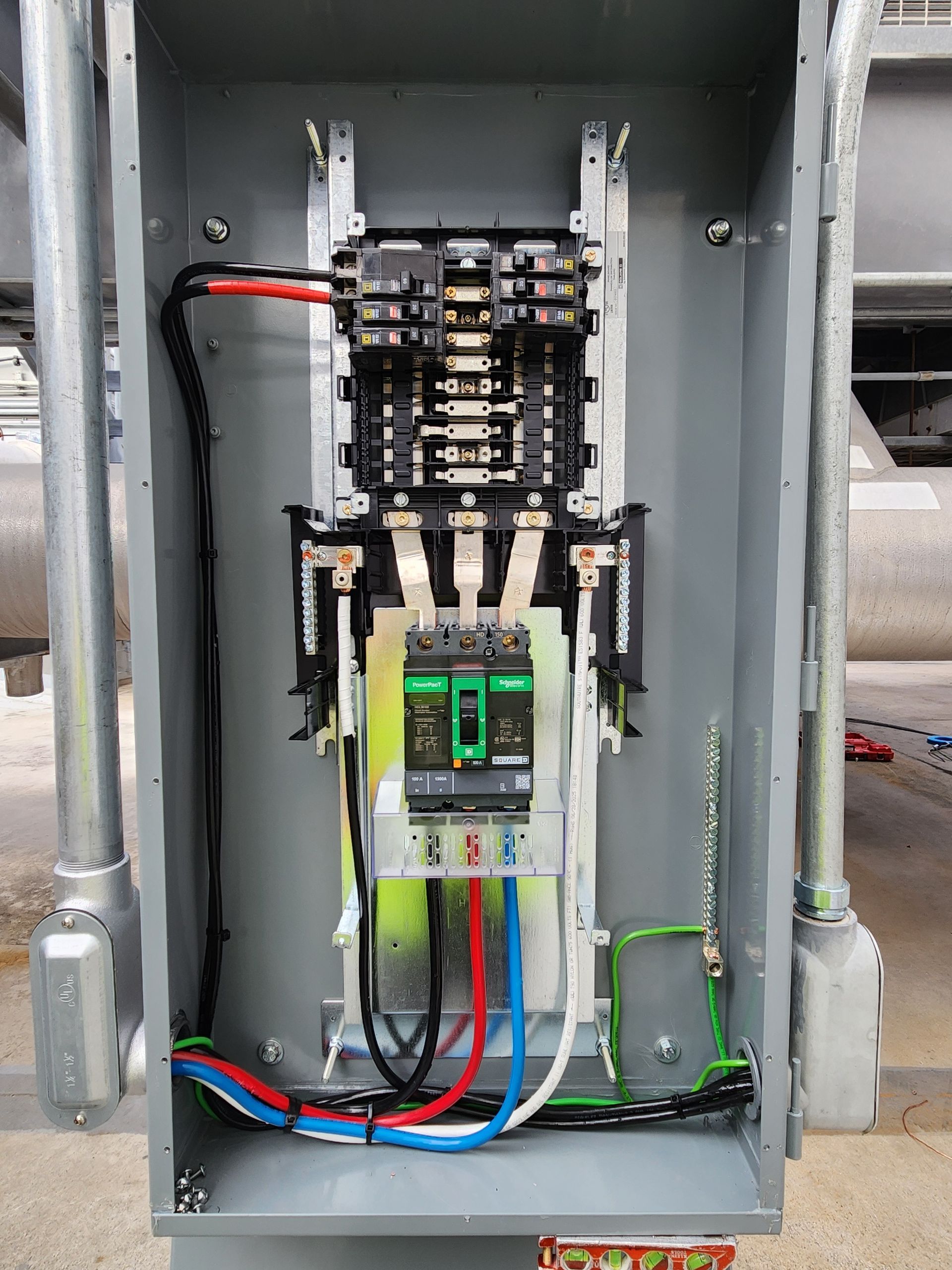 Open electrical panel with circuit breakers, wiring, and colored cables inside a metal cabinet