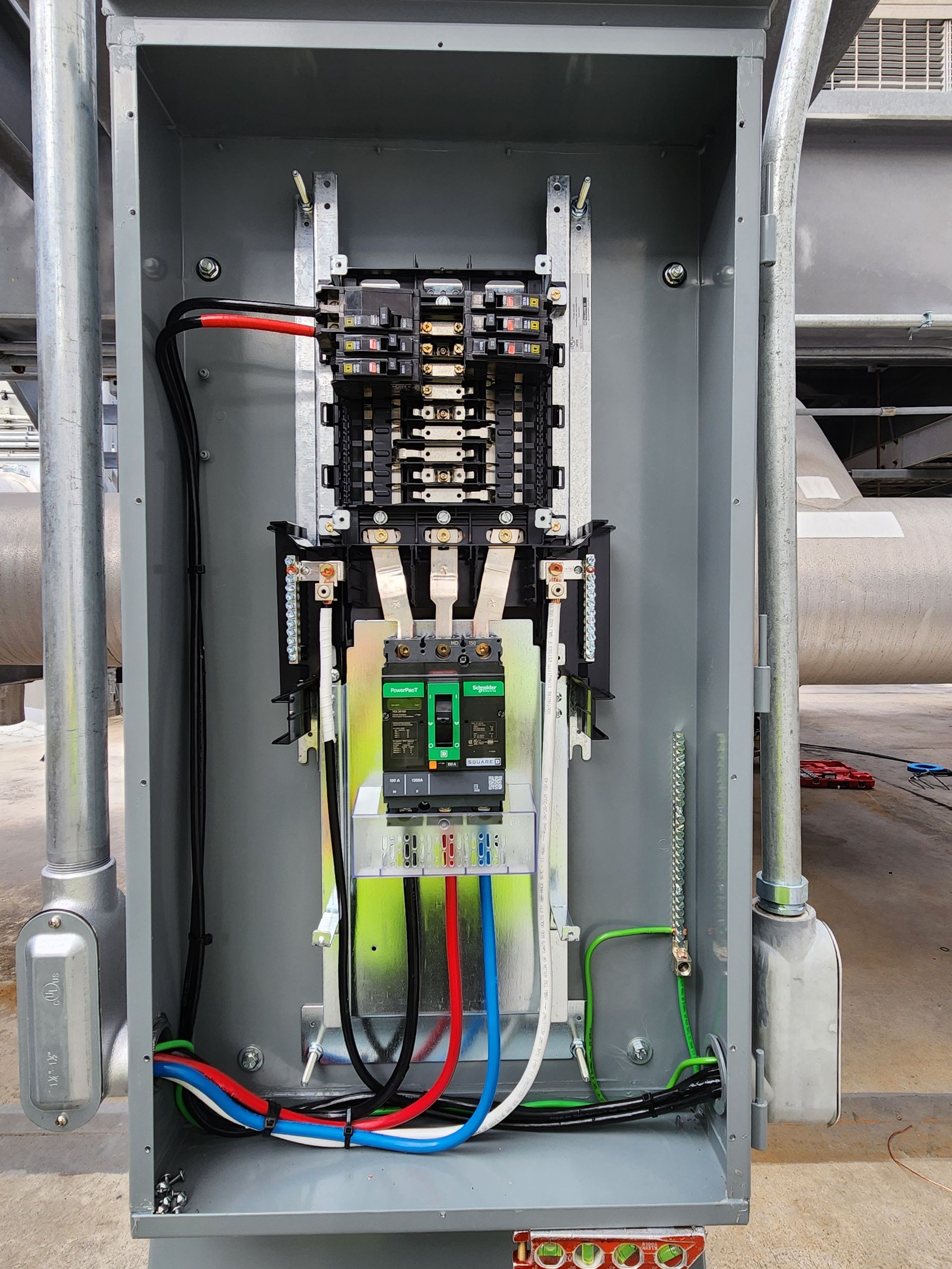 Open electrical control panel with wiring, relays, and circuit breakers inside a gray metal cabinet