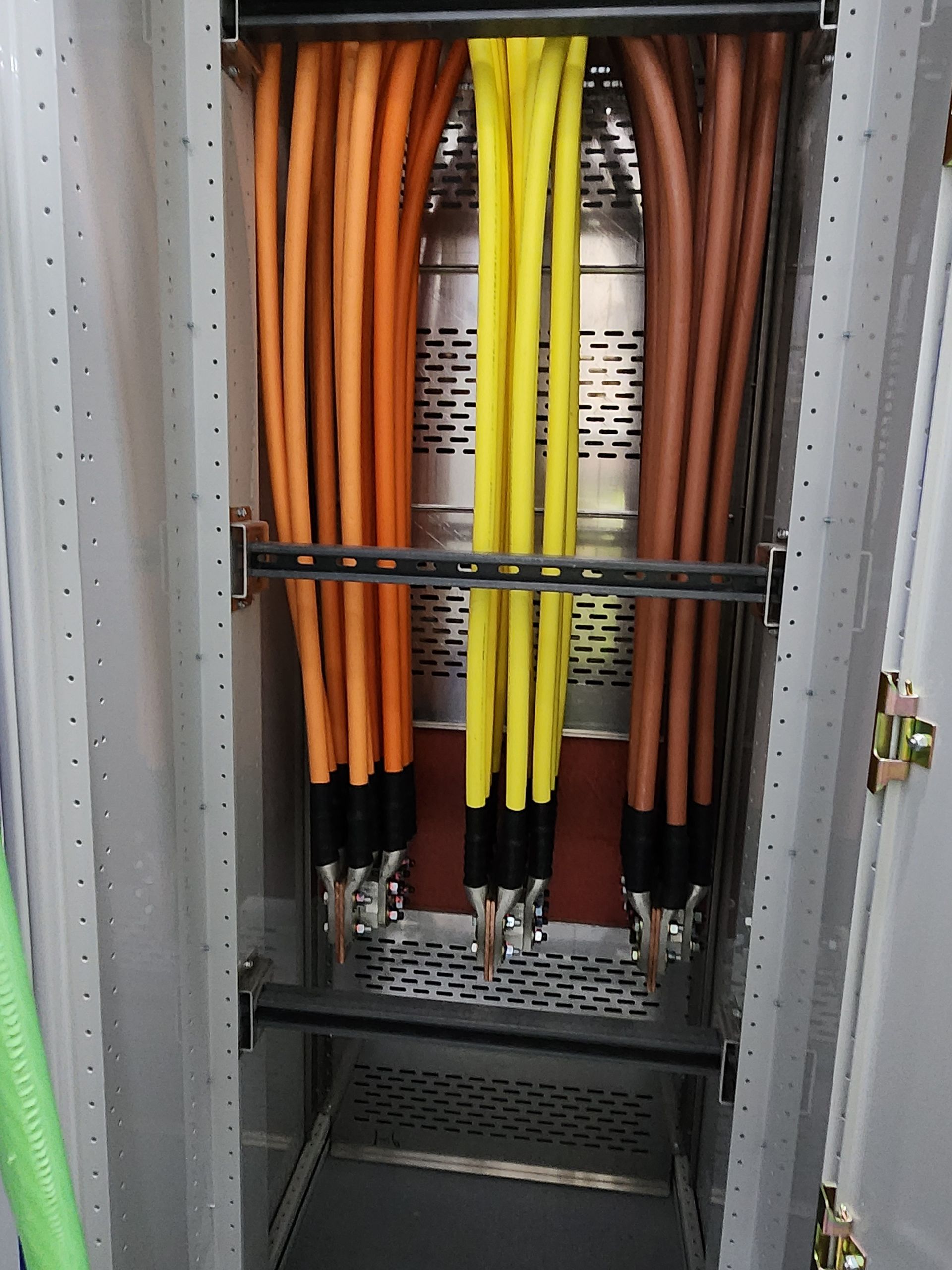 Open electrical cabinet with orange and yellow cables organized inside