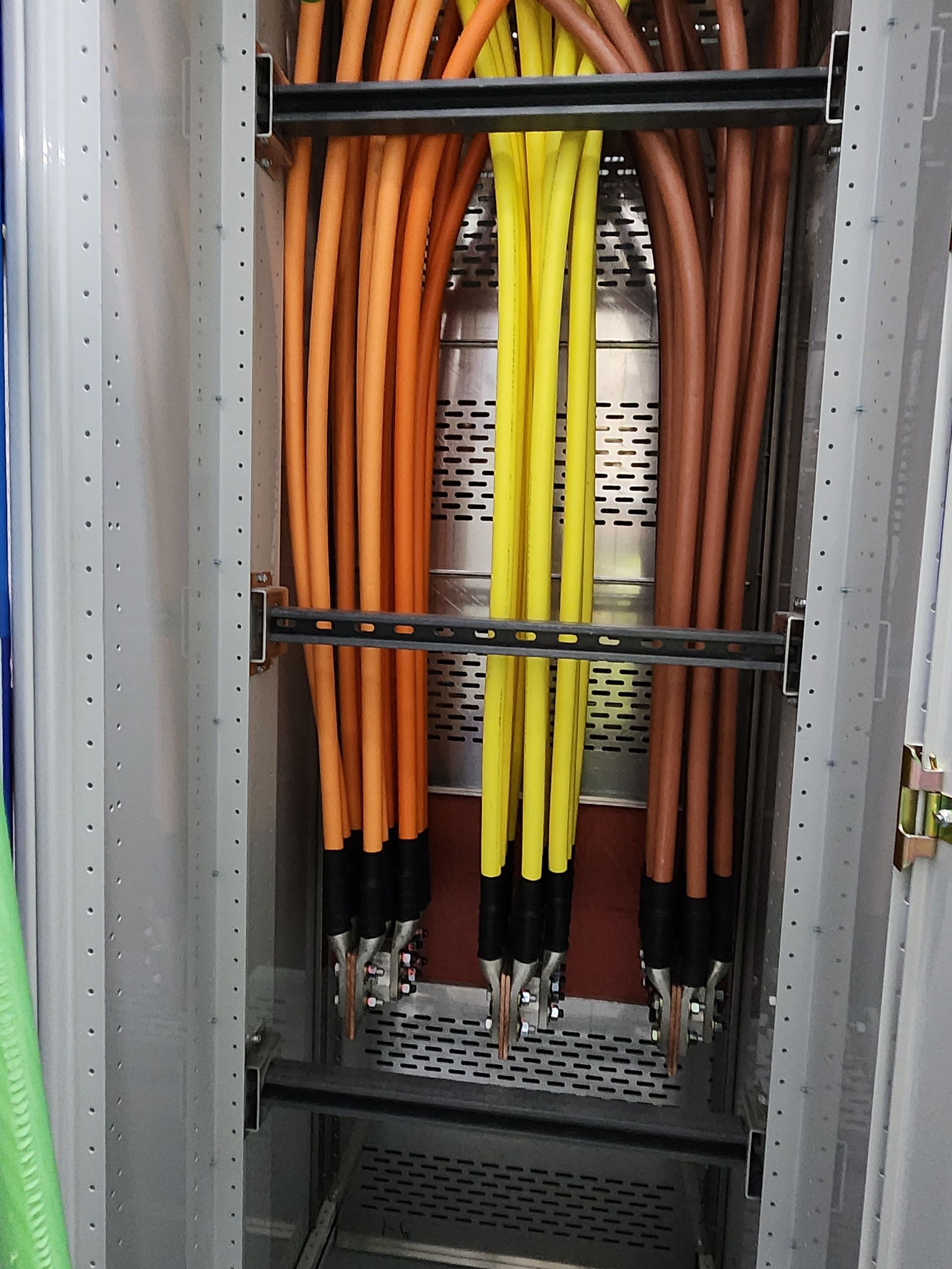 Electrical cables in a utility cabinet, bundled in orange, yellow, and brown.