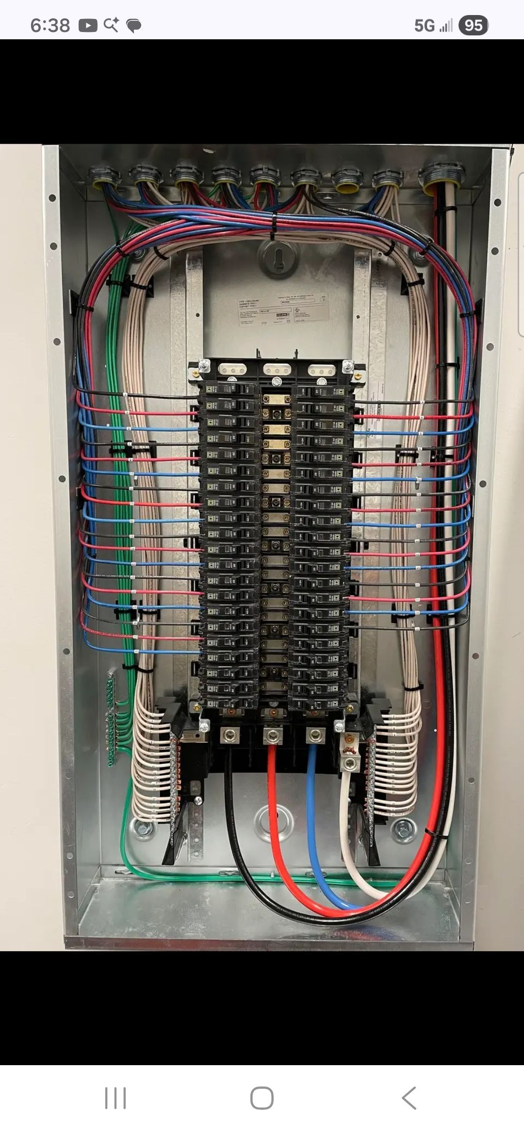Open electrical breaker panel with colored wires and circuit breakers inside a metal box