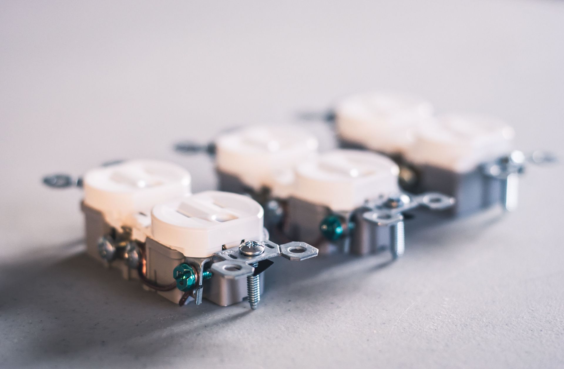 Small white quadcopter drones lined up on a gray surface with green lights on the front