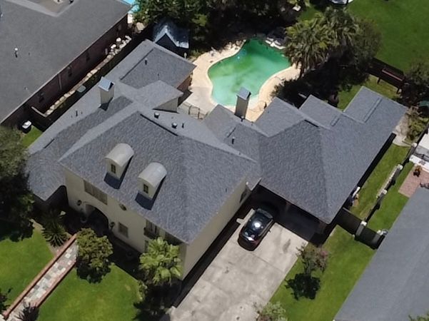 Aerial view of a suburban house with a driveway, garage, and backyard pool
