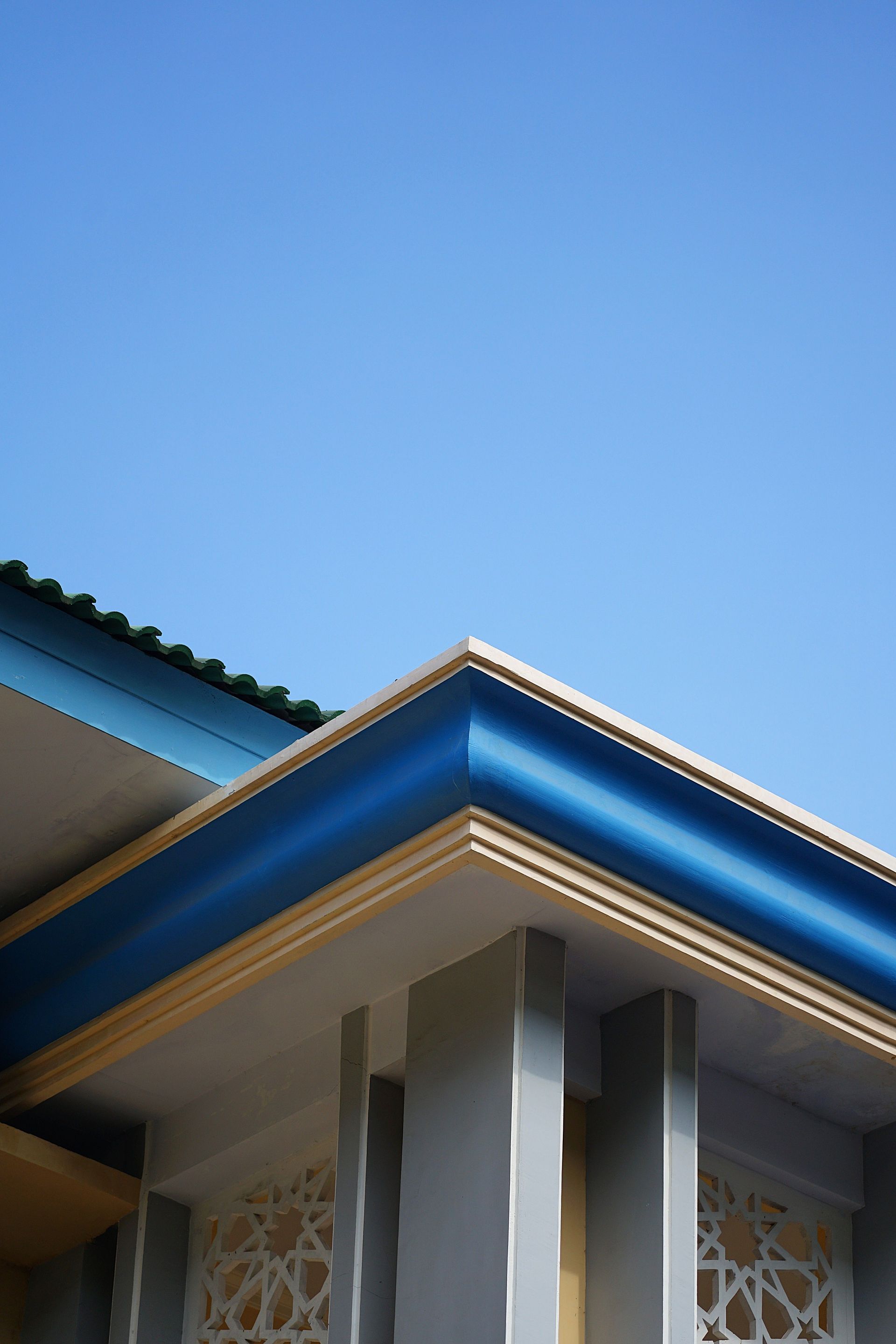 Blue house roofline against a clear blue sky