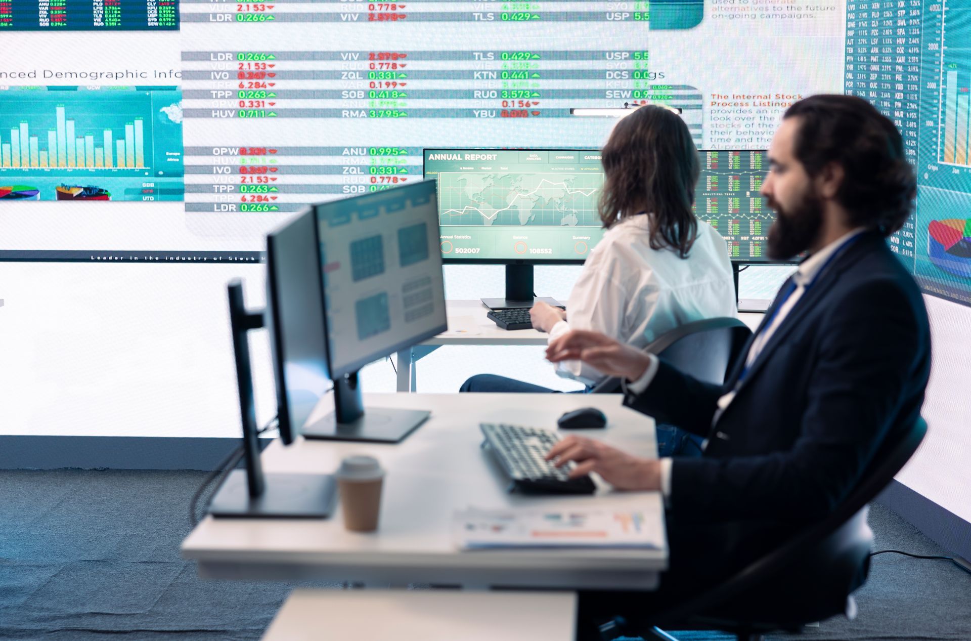 Analysts working at computers in a modern trading office with stock market dashboards on large screens