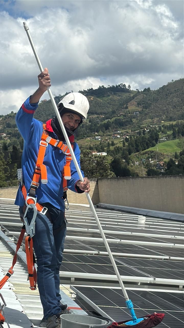 Trabajador instalando tejas en el techo de una casa con una pistola de clavos y un cinturón de herramientas.